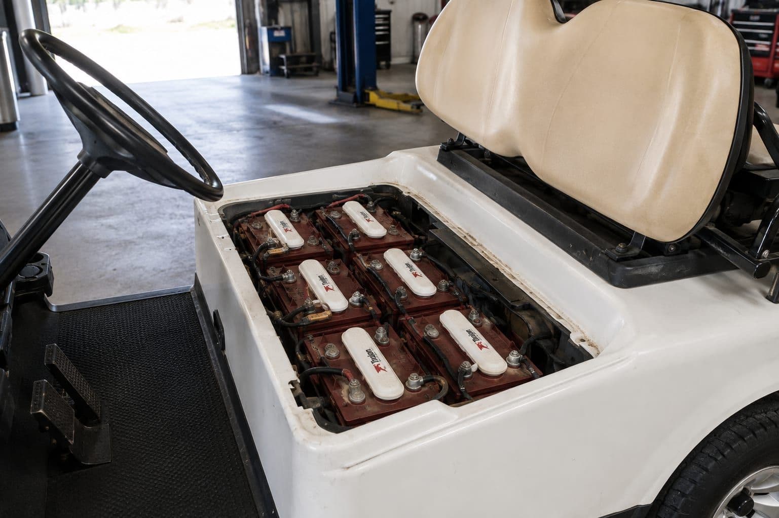 Carrito de golf con el asiento levantado y seis baterías Trojan instaladas en la bandeja
